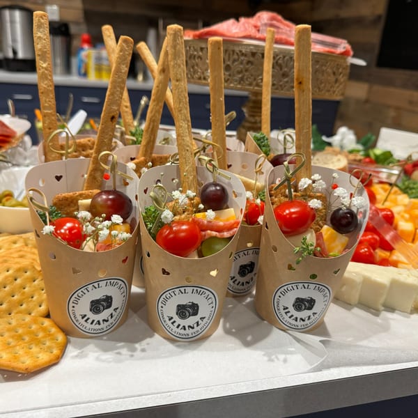 Several individual charcuterie cups with cheese, meat, grapes, tomatoes, and breadsticks, on a white tray.