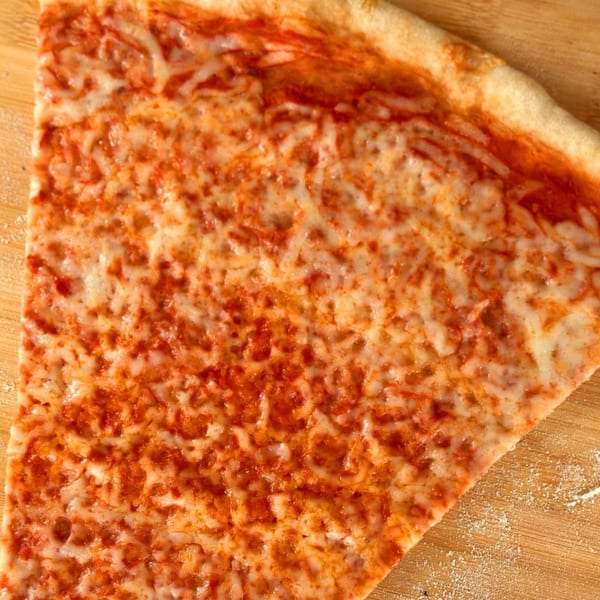 A close-up of a single slice of Why Not Pizza's classic cheese pizza on a wooden surface.