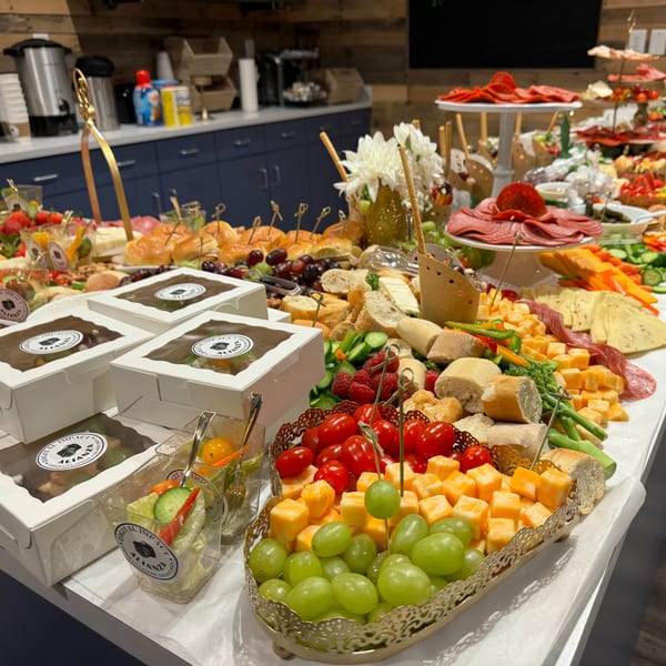 A large buffet table filled with various appetizers, including cheeses, meats, fruits, and small sandwiches.