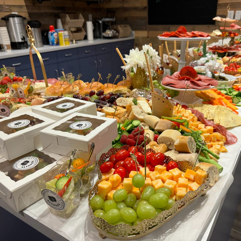 A large buffet table filled with various appetizers, including cheeses, meats, fruits, and small sandwiches.