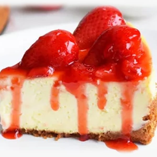 A slice of strawberry cheesecake with a graham cracker crust, drizzled with strawberry sauce.